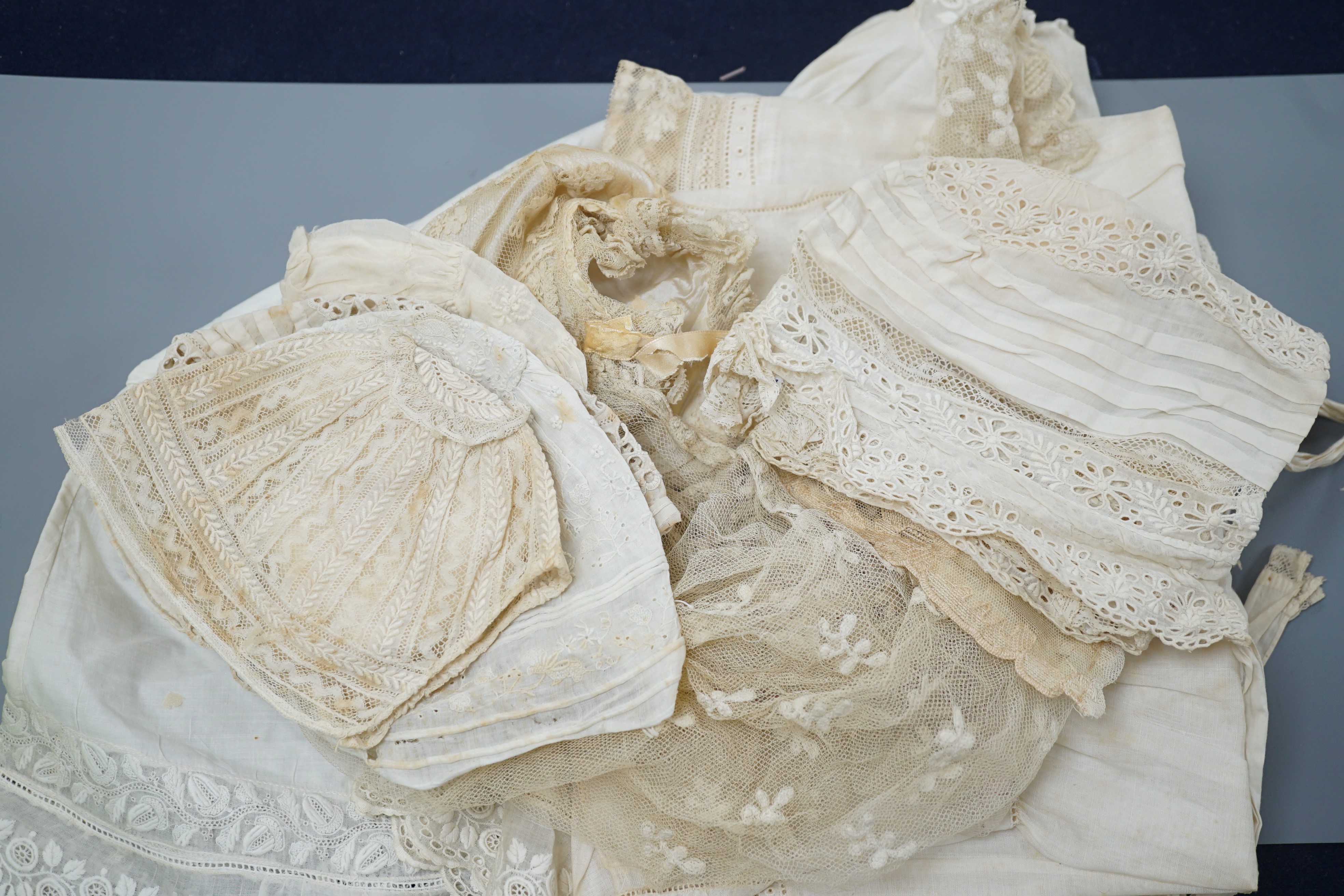 A collection of 19th century babywear, lace and cutwork bonnets and a christening bonnet and veil